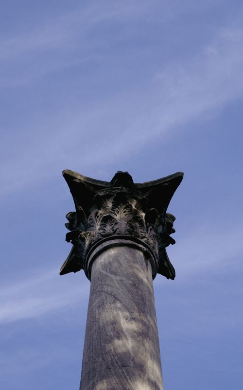 Free A classic Corinthian column stands prominently against a clear blue sky. Architectural beauty. Stock Photo