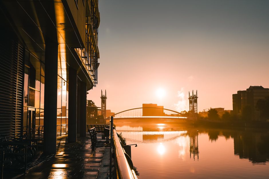 Stunning sunrise reflecting over Salford Quays, capturing modern urban architecture in warm tones.