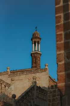 A beautifully preserved historic minaret under a clear blue sky in Midyat, Mardin.