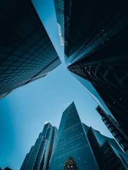 Looking up at modern skyscrapers against a blue sky in London's financial district.