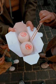 People enjoying traditional bao buns outdoors in Chinatown, London.