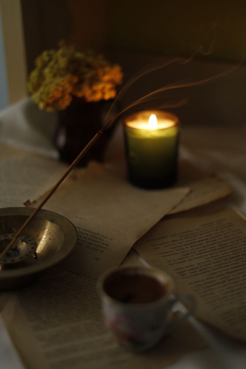 Free Warm candlelit scene with incense, tea, and open books for cozy ambiance. Stock Photo