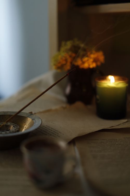 Free A serene scene of a lit candle, incense, and flowers creating a cozy atmosphere. Stock Photo