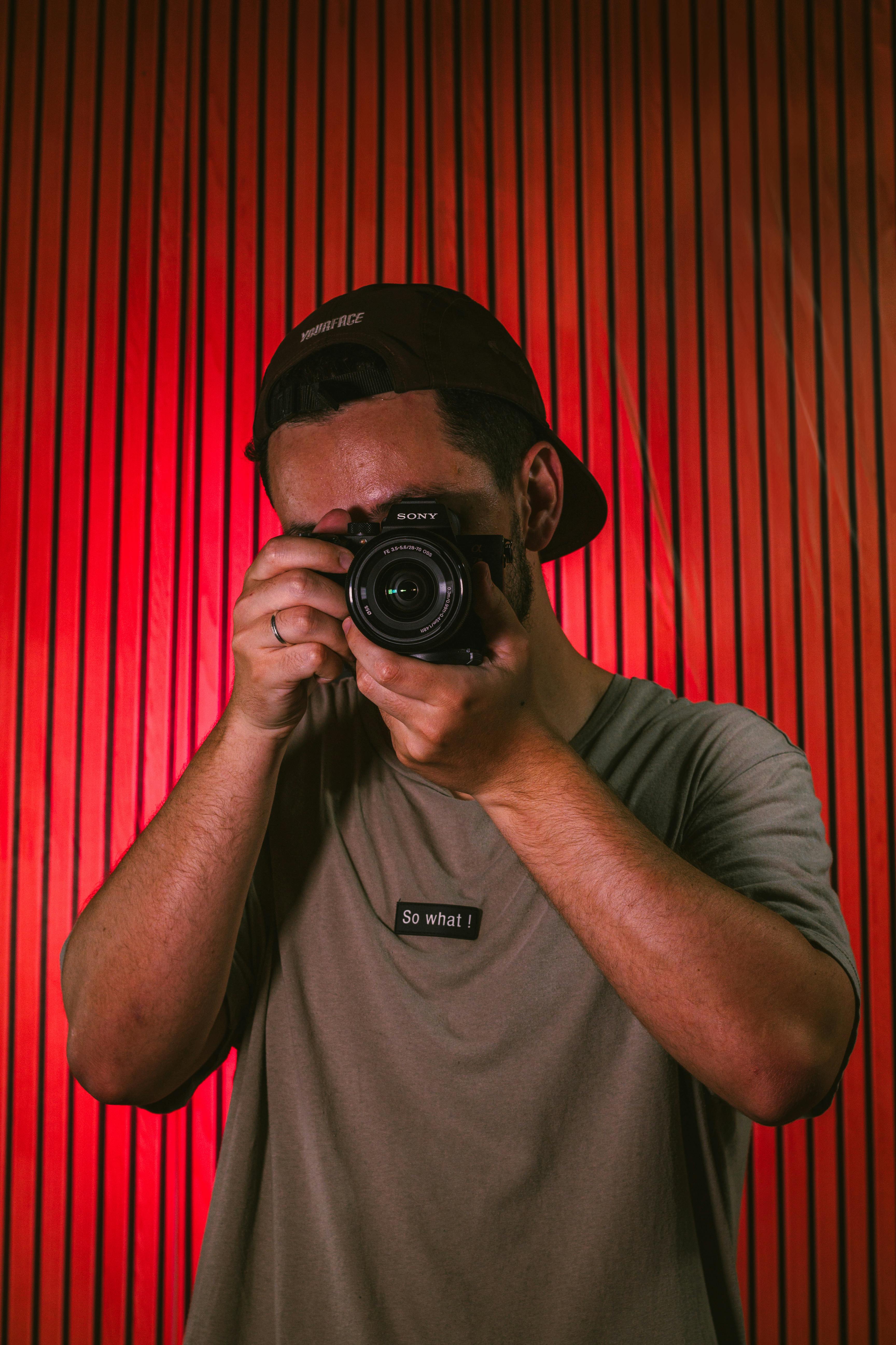 A photographer captures a moment using his camera against a wooden backdrop.