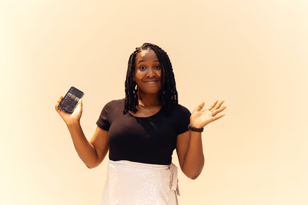 Nigerian woman with braids smiling while holding a smartphone in Lagos