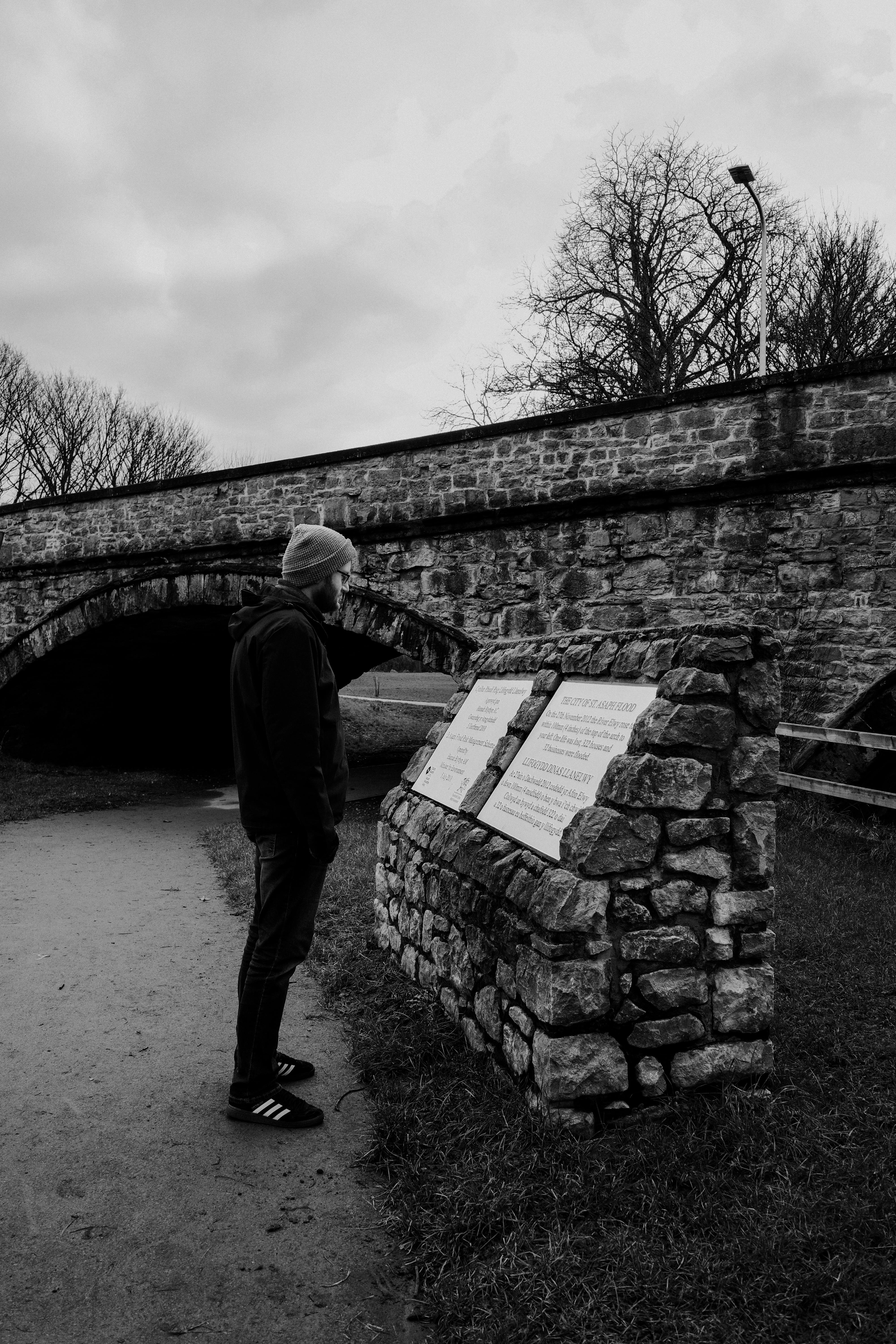 man observing historical stone bridge signage