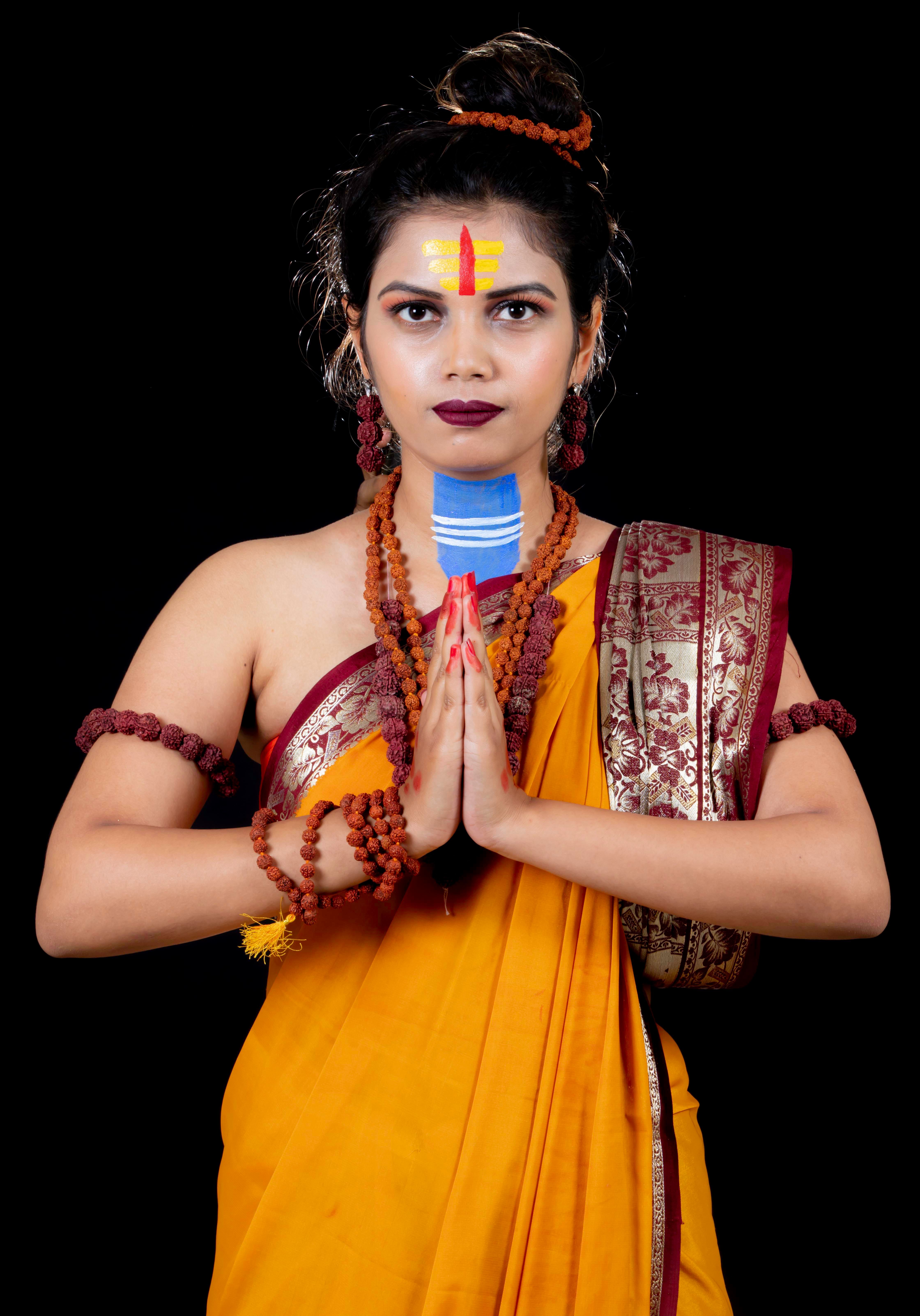 Portrait of a woman in traditional Indian clothing performing a prayer gesture.