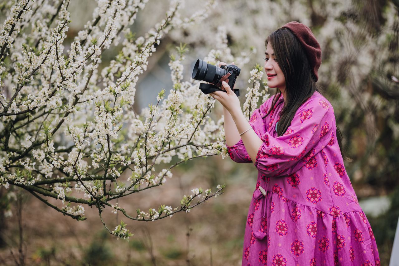 female photographer capturing spring blossoms in full bloom outdoors