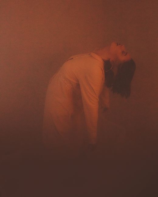 Sensual backlit silhouette of woman in fog, creating a moody atmosphere.