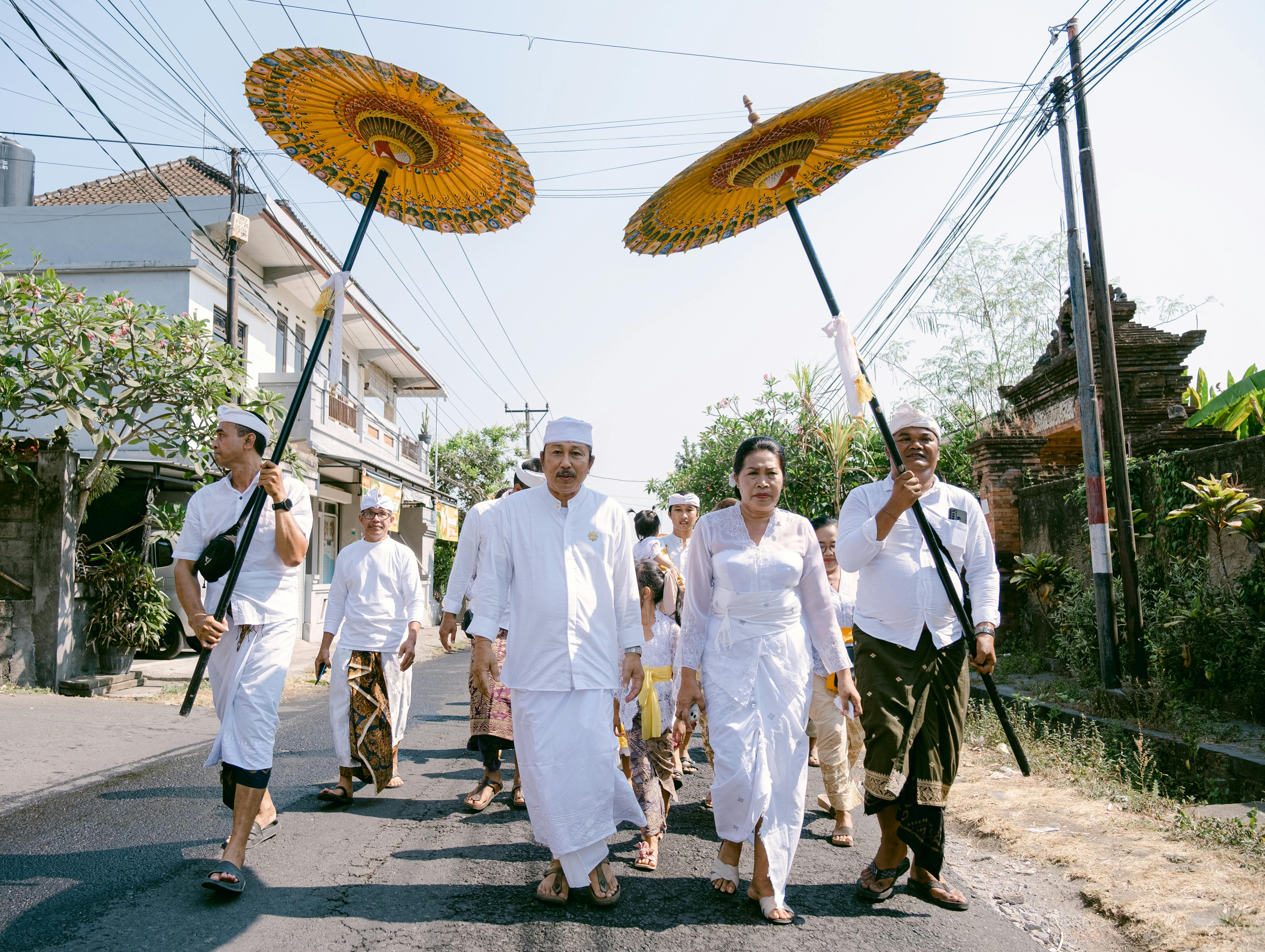 A group of Balinese people in traditional attire participate in a cultural procession.