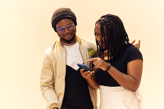 A man and woman smiling as they look at a smartphone outdoors in Lagos, Nigeria.