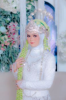 Woman in ornate traditional attire with beaded headdress, vibrant floral background.