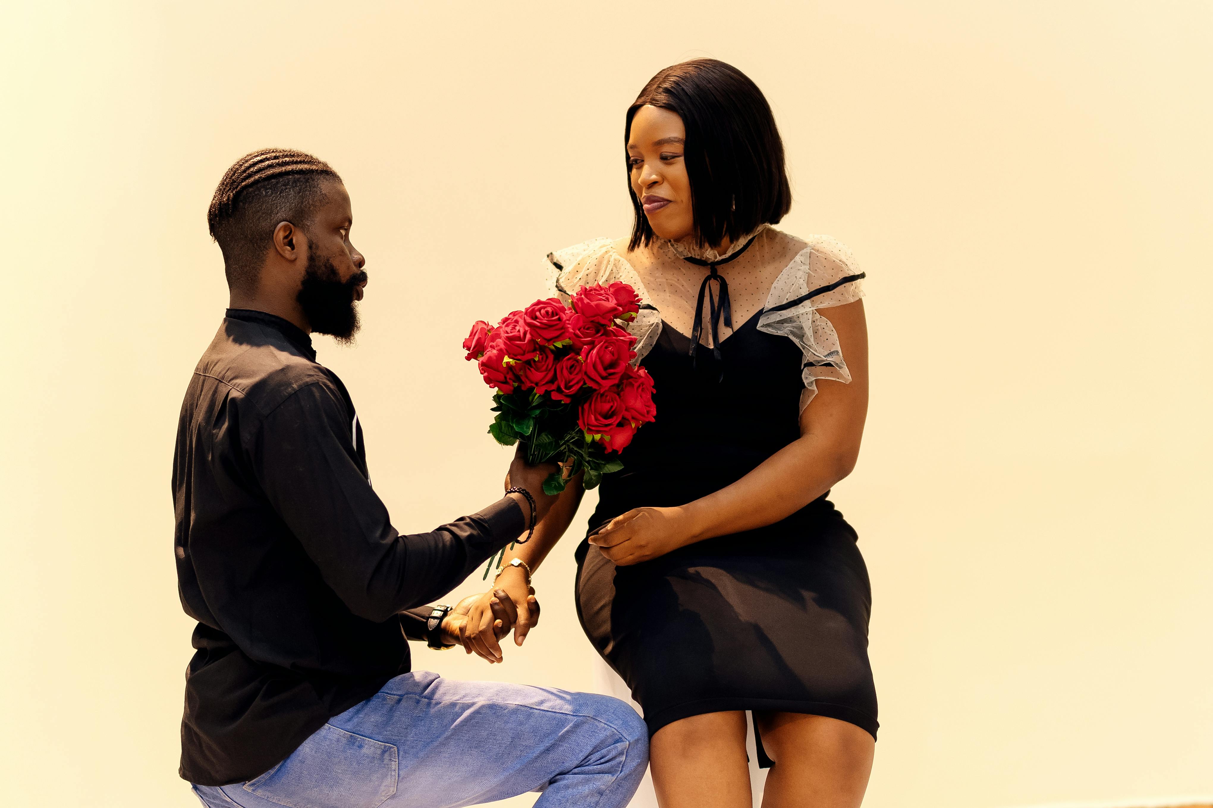 A romantic couple in Lagos featuring a man kneeling with red roses, signifying love and affection.