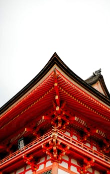 A detailed view of a traditional Japanese temple rooftop with vibrant red and intricate design.