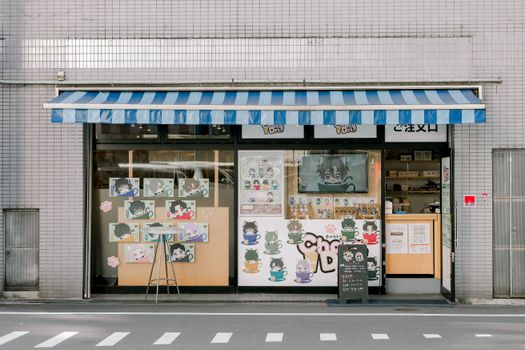 Anime-themed storefront with colorful characters and striped awning.