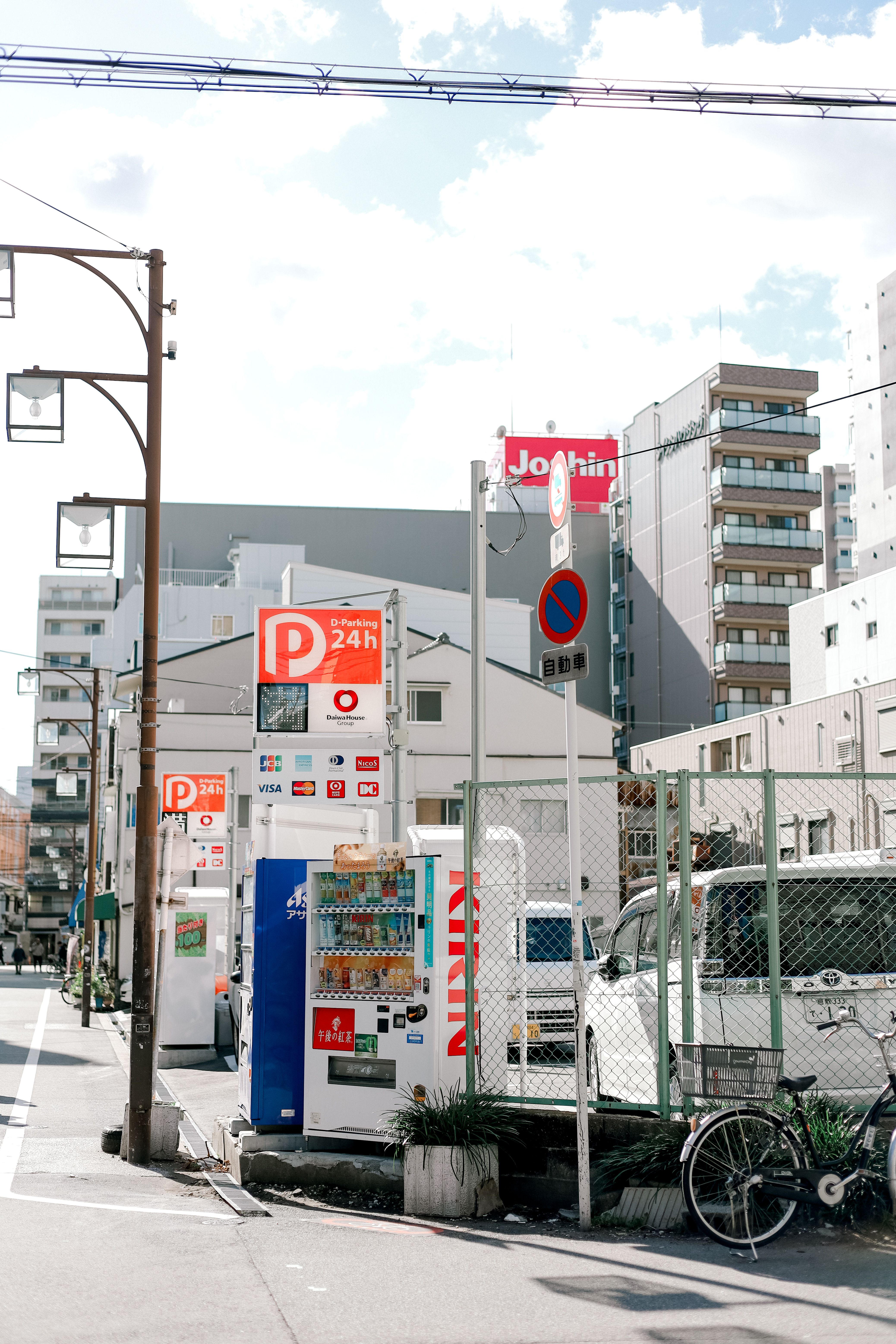 A busy urban street in Japan with vending machines and modern buildings, captured during the day.