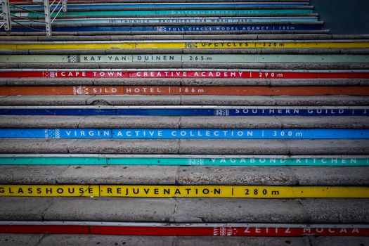 Vibrant staircase featuring city spots direction markers in colorful urban landscape.