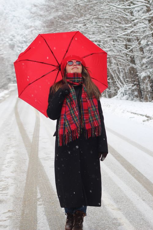 Free A woman walking with a red umbrella on a snow-covered road in Bolu, Türkiye. Stock Photo