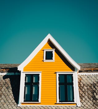 Charming yellow house with slate roof and white trim under a bright blue sky.