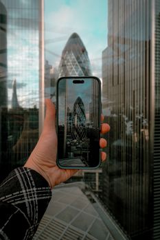 A creative shot of The Gherkin captured through a smartphone in London's urban landscape.