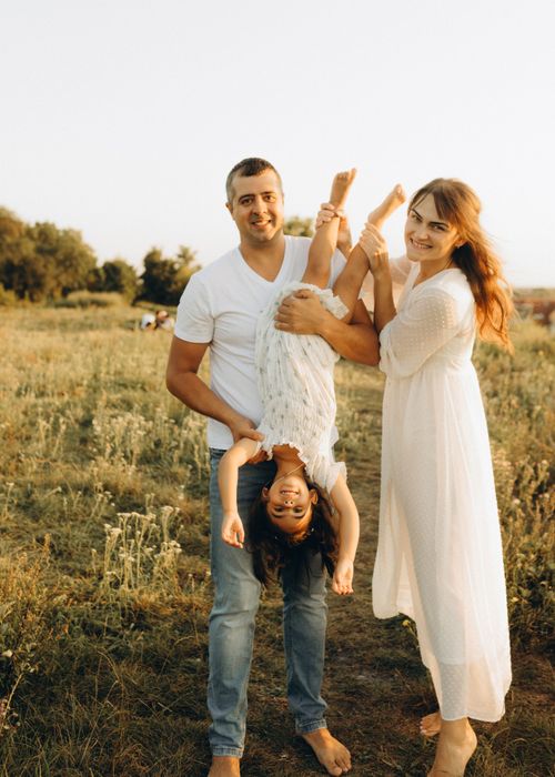 Free A joyful family playing together in a sunny outdoor field. Stock Photo