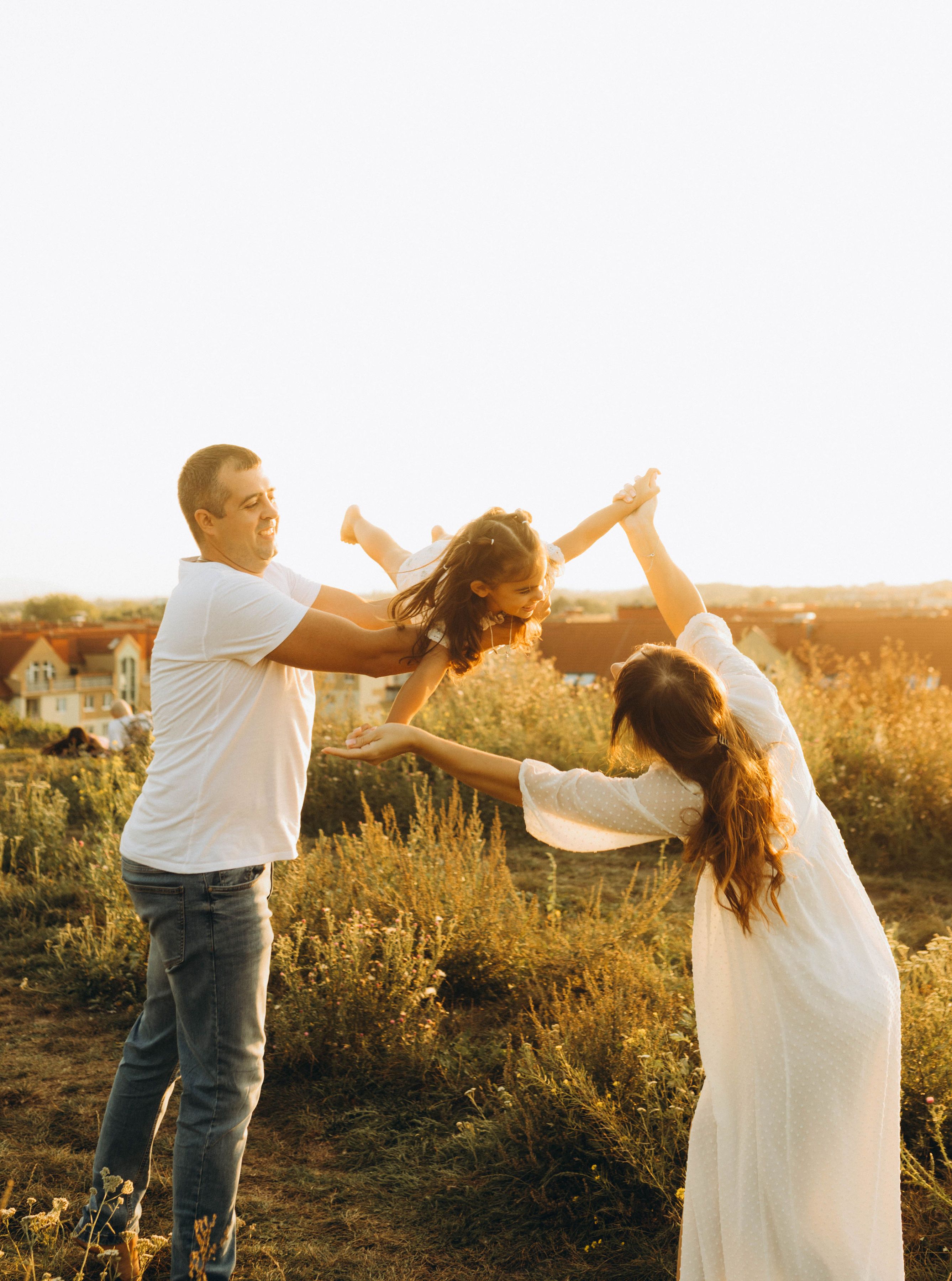 A happy family playing together in a sunny field during sunset.