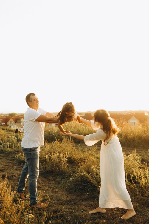 Free A joyful family playing together in a sunny grassy field, highlighting warmth and togetherness. Stock Photo