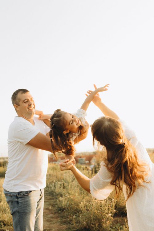 Free Joyful family playing outdoors at sunset, capturing a moment of happiness and connection. Stock Photo