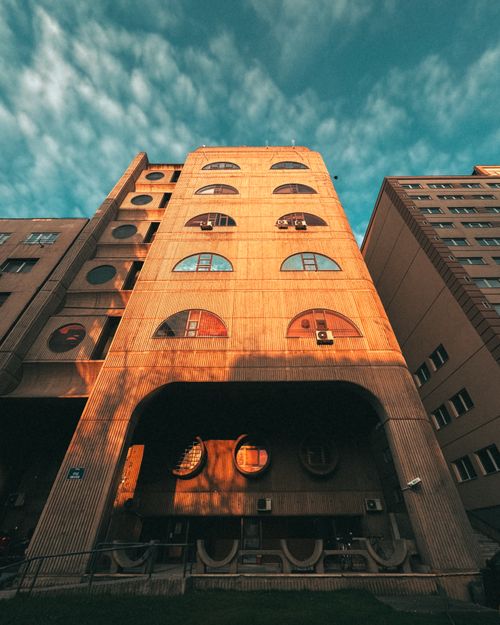 Free Low angle view of a modern building facade with round windows at sunset. Stock Photo