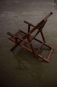 A solitary wooden chair sits in the wet sand of a Brazilian beach, evoking serenity.