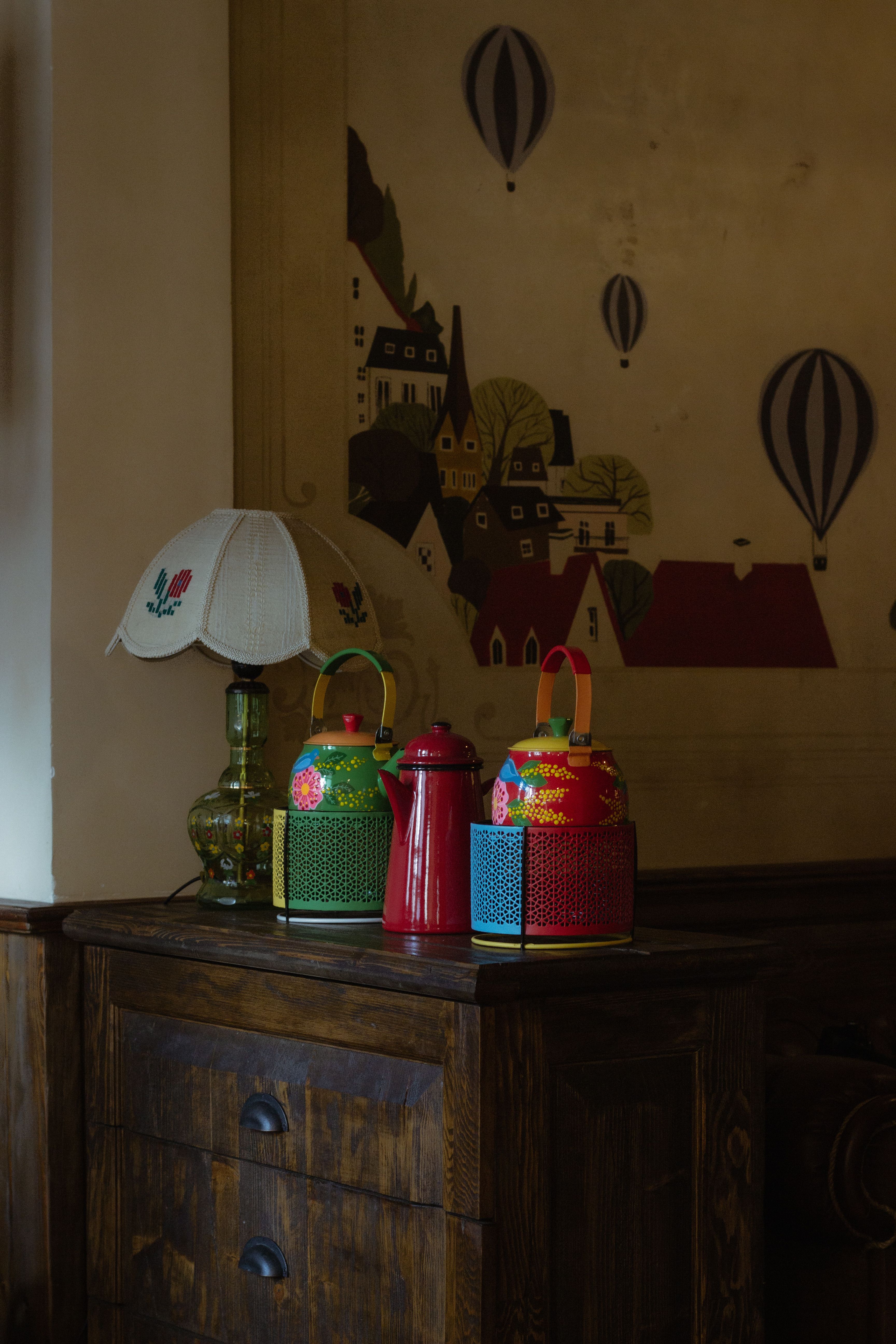 Cozy indoor scene featuring colorful vintage tins and a stylish lamp on a wooden cabinet.