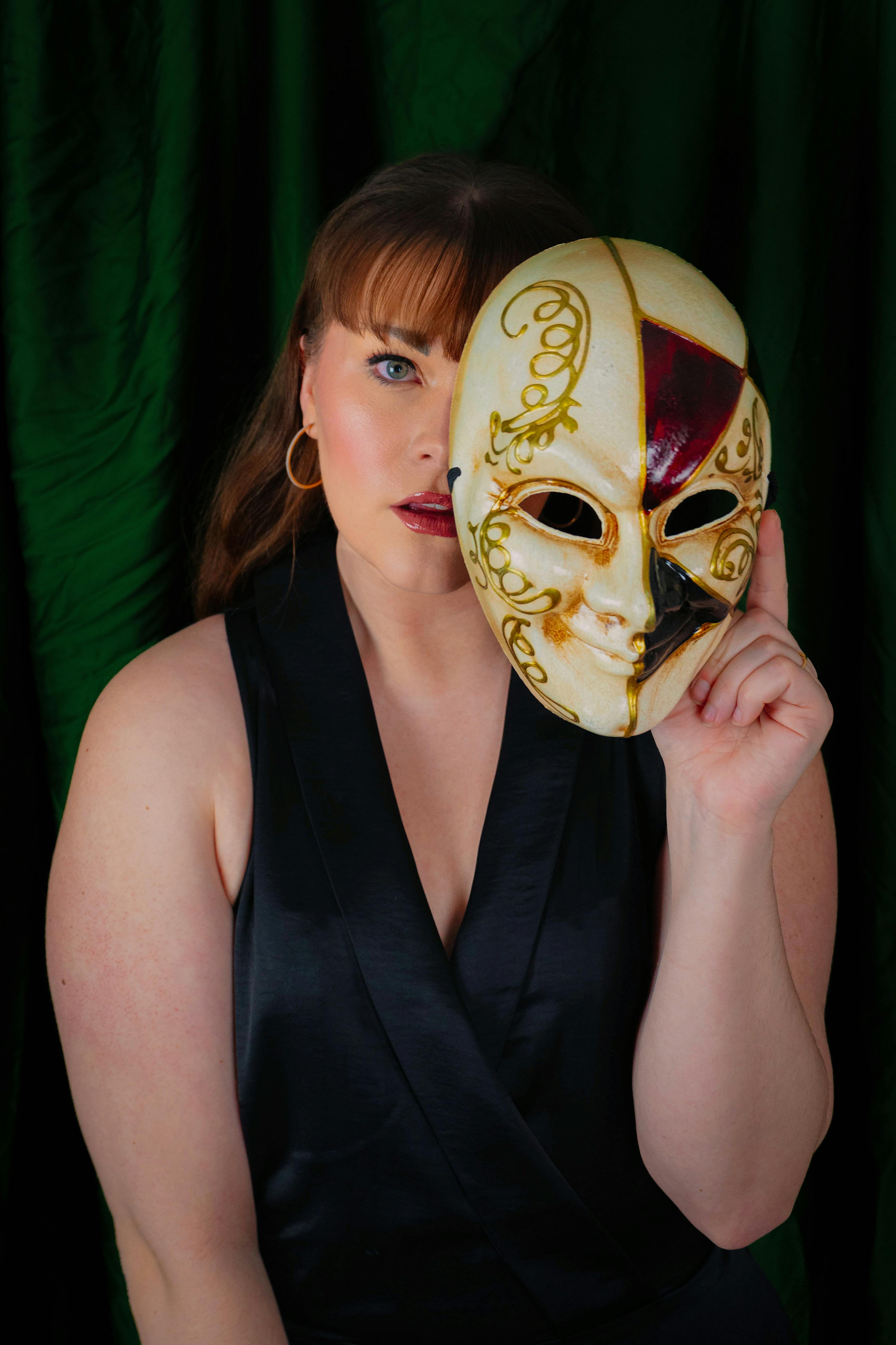 Free A captivating portrait of a woman holding a Venetian mask, conveying mystery and elegance. Stock Photo