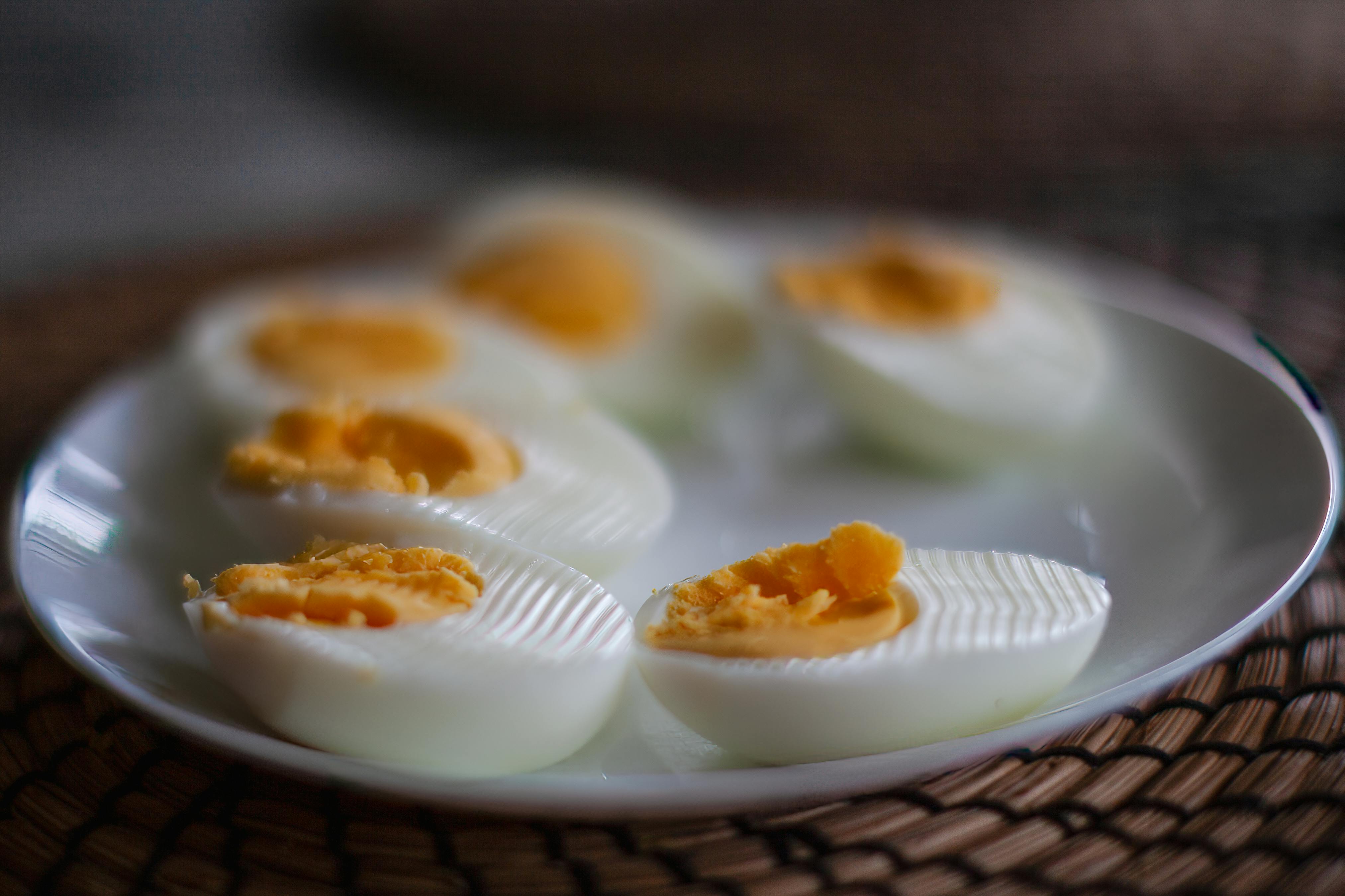 Close-up of sliced boiled eggs with soft yolks on a white plate, perfect breakfast or snack idea.