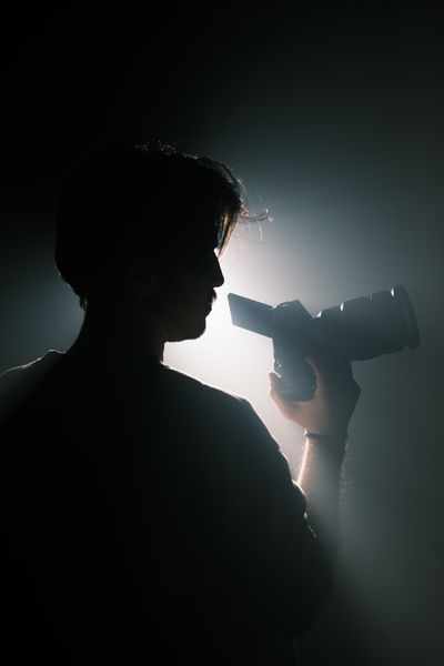 Silhouette holding a camera in dramatic light, photo by Cemrecan Yurtman on Pexels