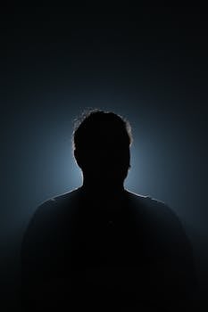 A silhouette of a mysterious figure illuminated by backlight, creating a dramatic and moody effect.