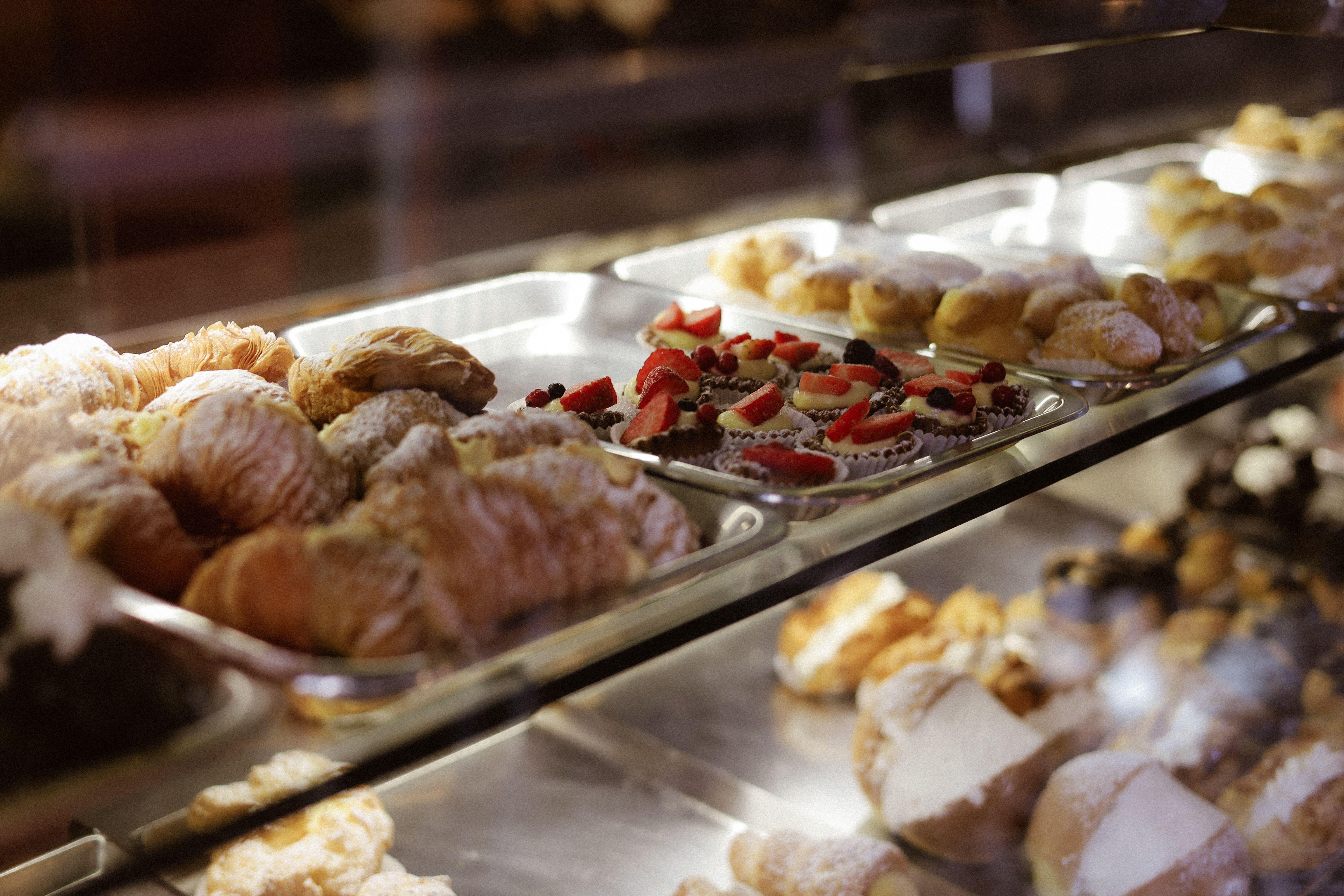 Assorted pastries including croissants and tarts displayed in a bakery case.