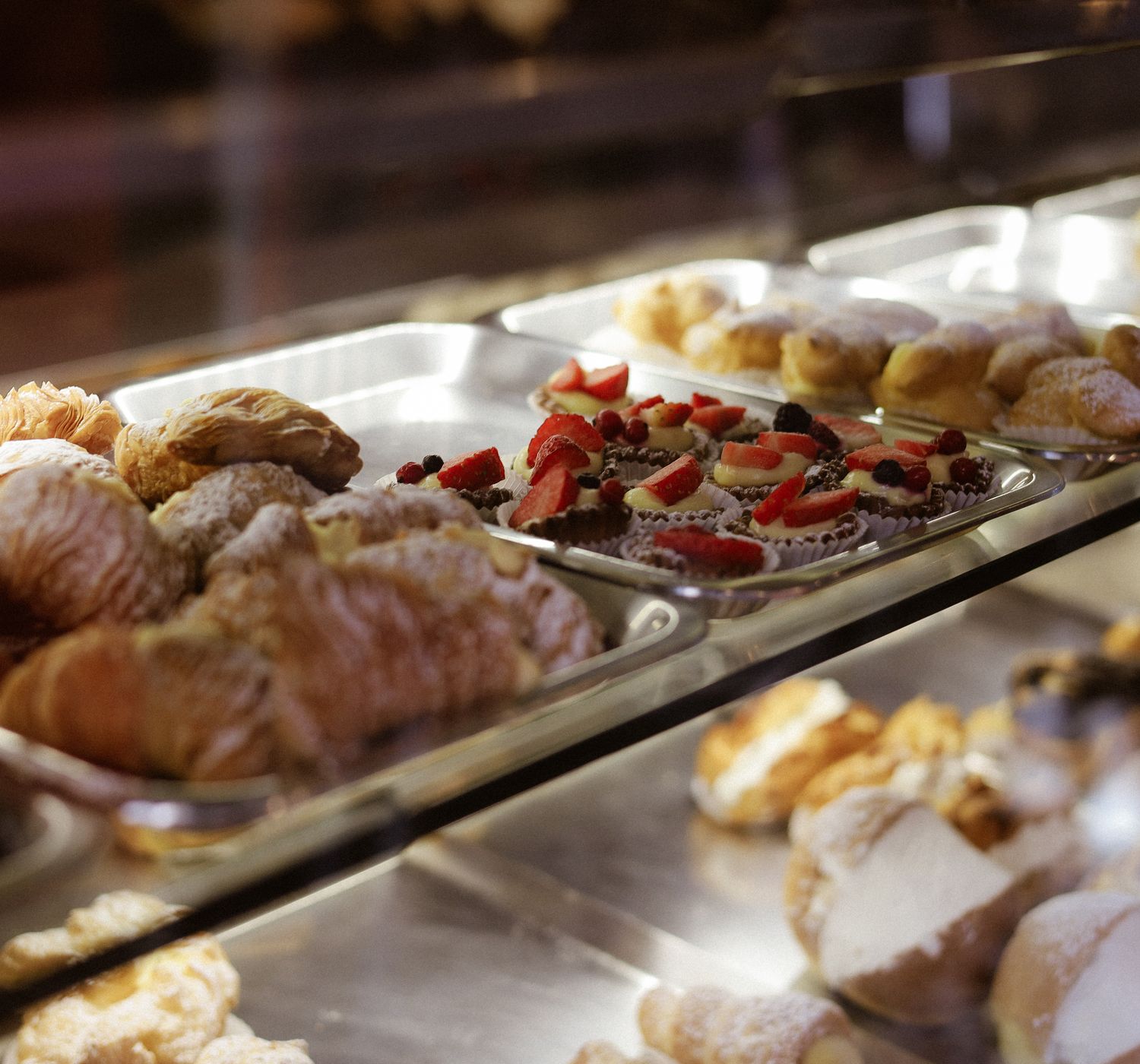 Assorted pastries including croissants and tarts displayed in a bakery case.