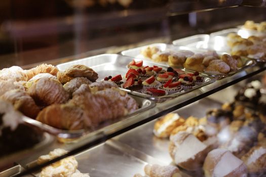 Assorted pastries including croissants and tarts displayed in a bakery case.