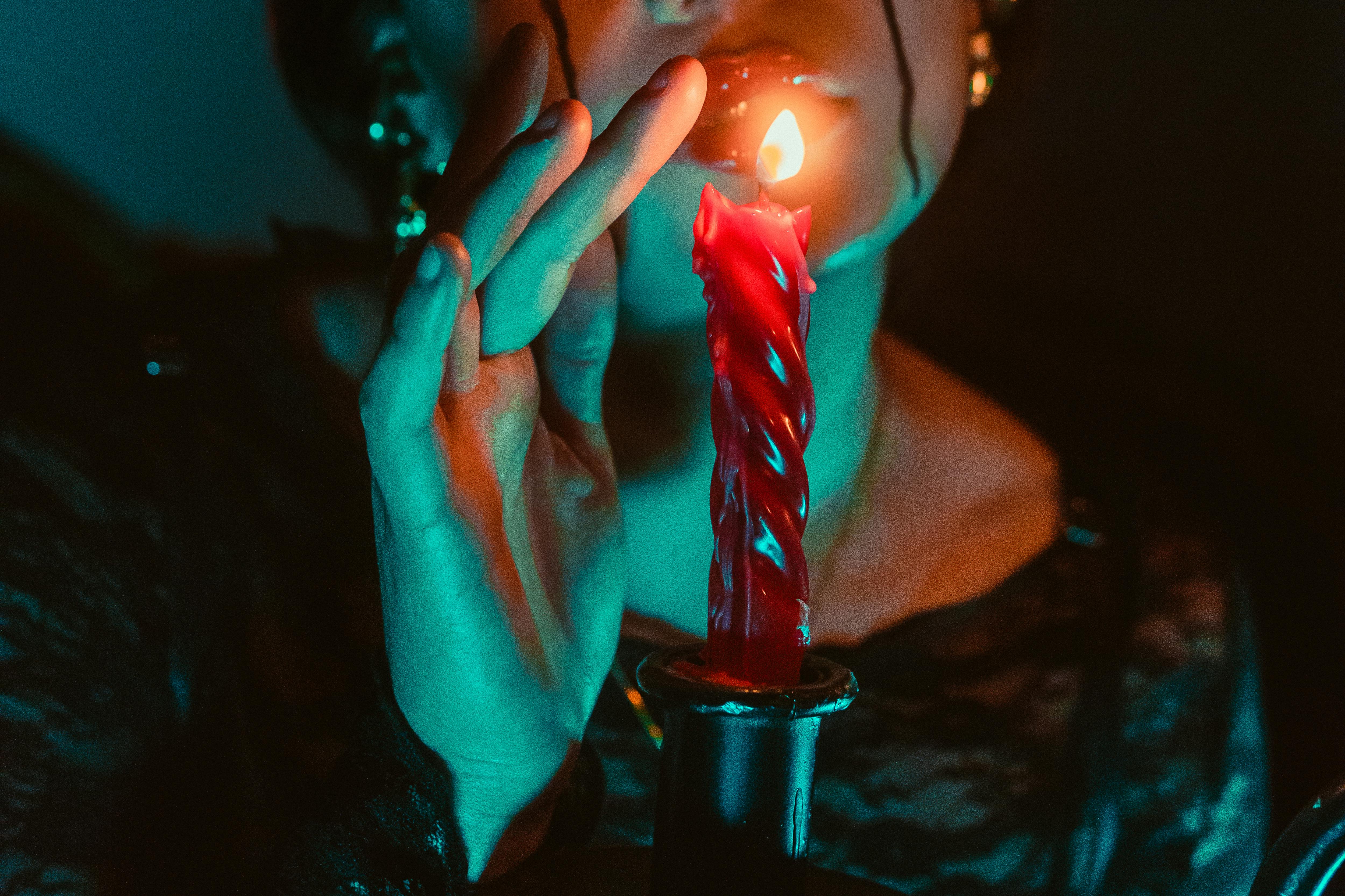 An atmospheric portrait featuring a person and a lit candle, casting shadows and a gothic vibe.