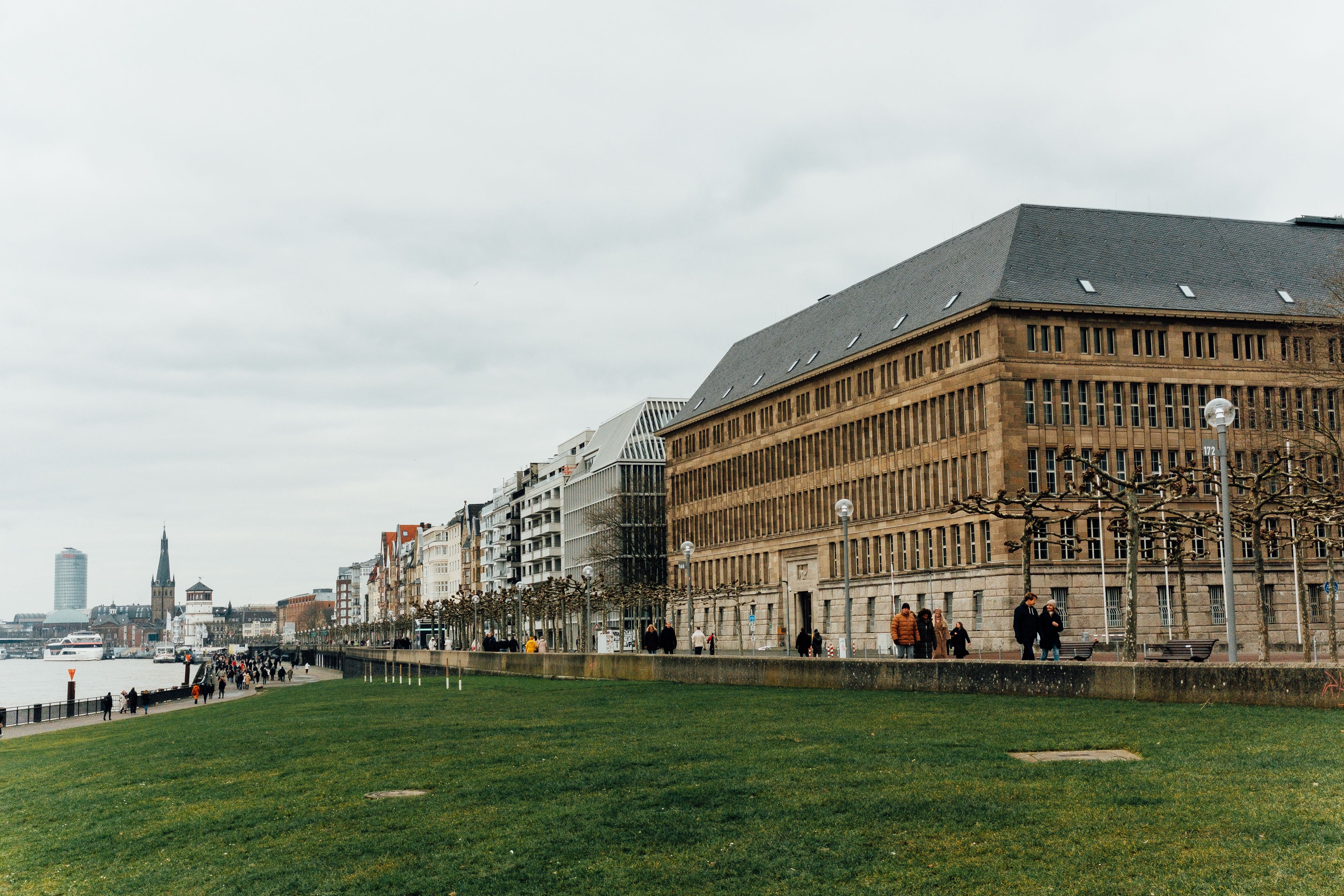 A level riverside promenade with modern hotel blocks behind, wide smooth paving