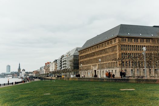 Peaceful urban park with historical and modern European architecture along a waterfront.