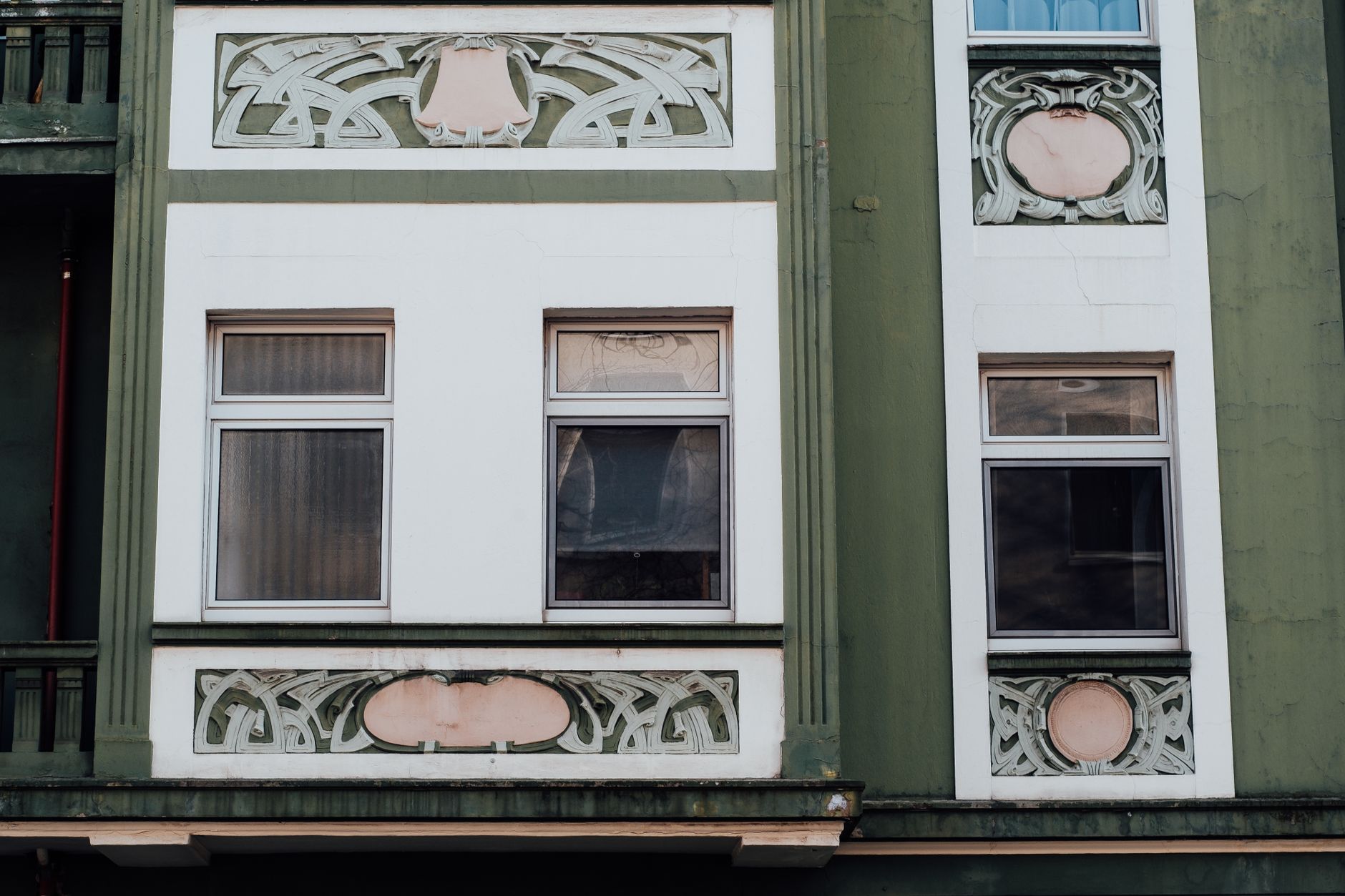 Close-up of a historic green and white Art Nouveau building facade with intricate decorative details.