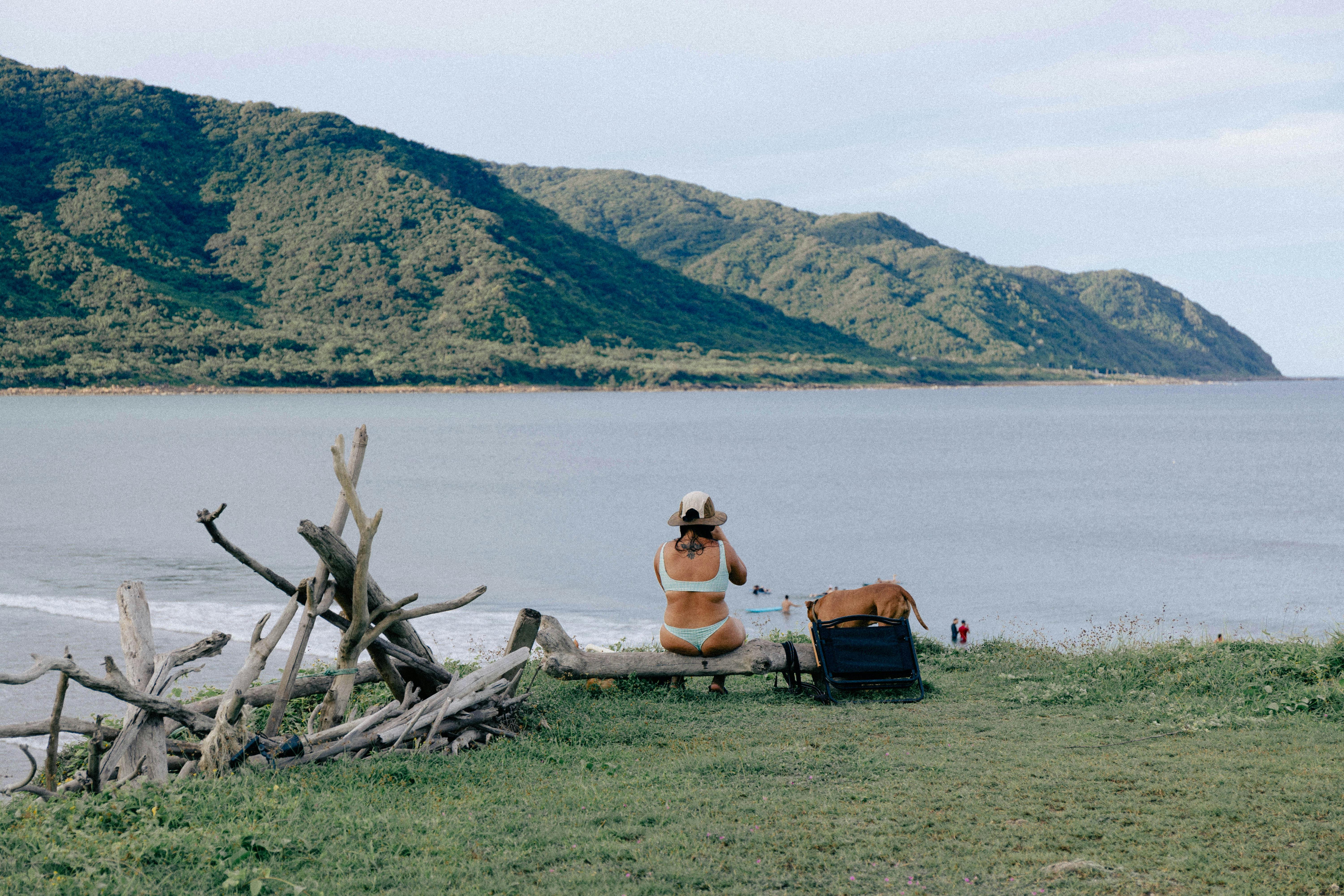 Woman enjoying a serene beach view with mountains in Taiwan, perfect for relaxation.