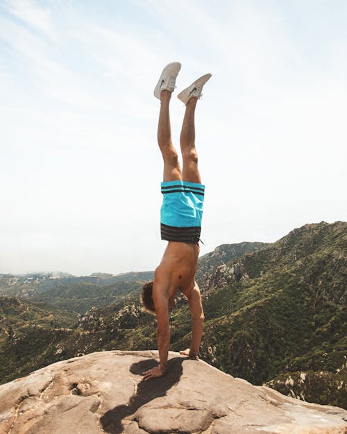 Man Doing Upside Down on Mountain Cliff