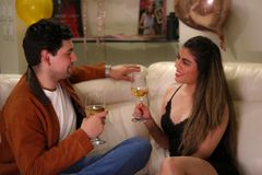 A relaxed indoor evening with two adults enjoying glasses of white wine.
