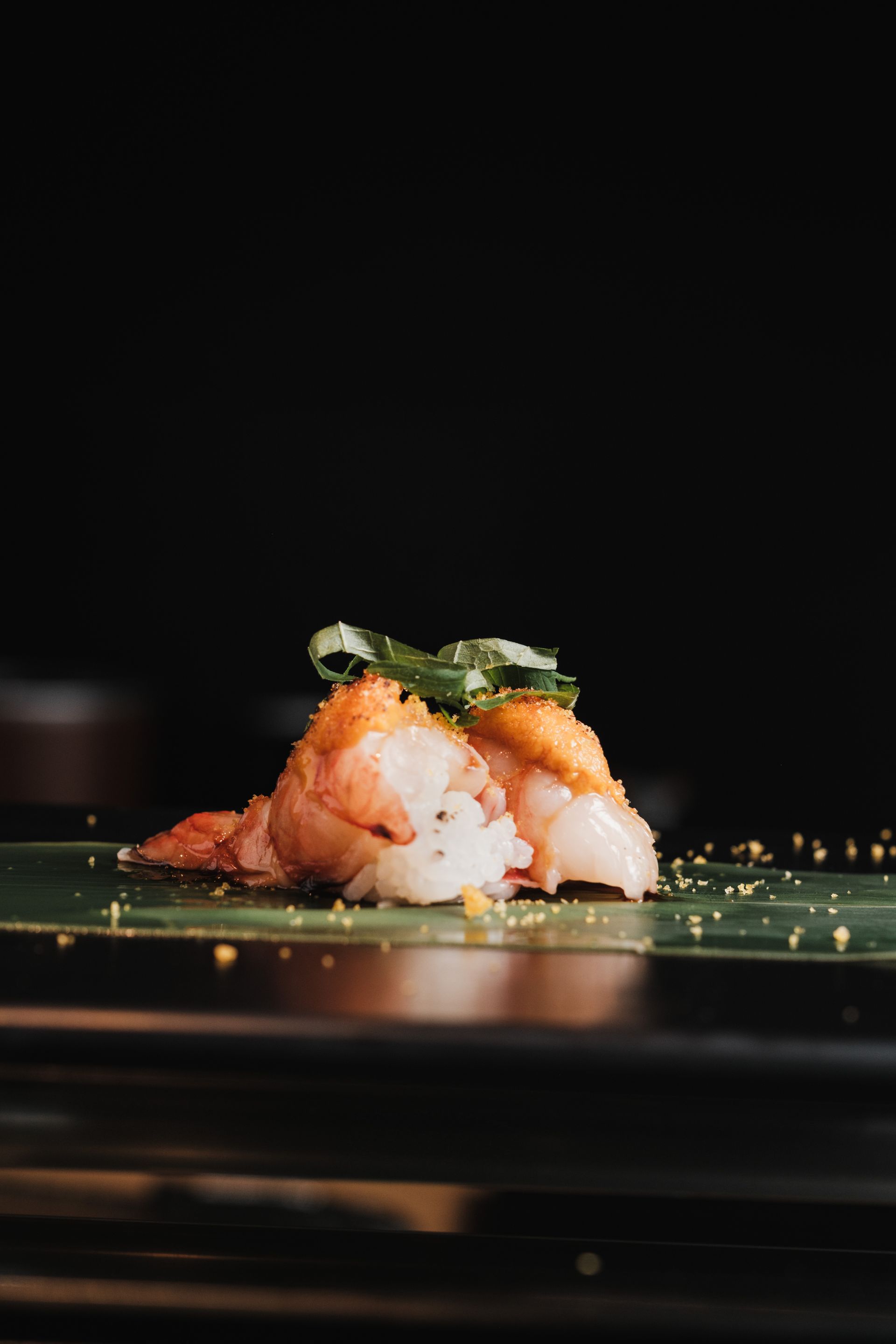 Đầu bếp chuẩn bị omakase tại quầy sushi, ánh sáng ấm buổi tối