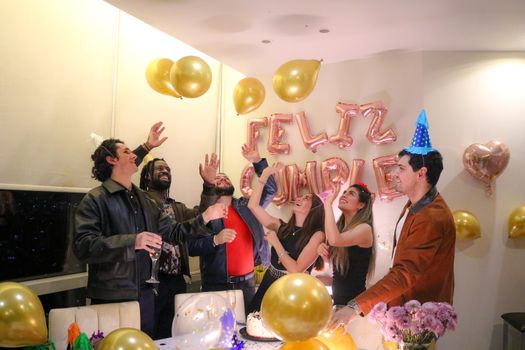 A lively indoor birthday party with friends, balloons, and decorations.