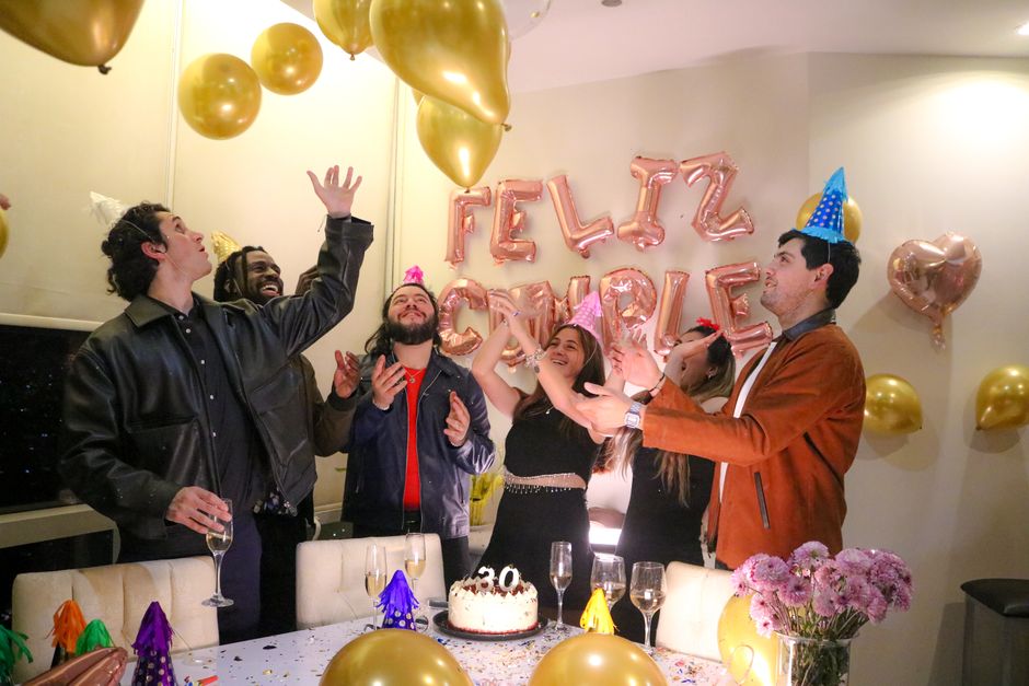 Fotomural Grupo de amigos celebrando un cumpleaños en el interior con globos y pastel.