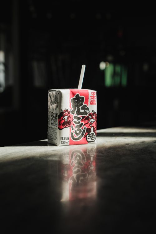 Free Cube-shaped drink package with Japanese design lit in a shadowy room. Stock Photo
