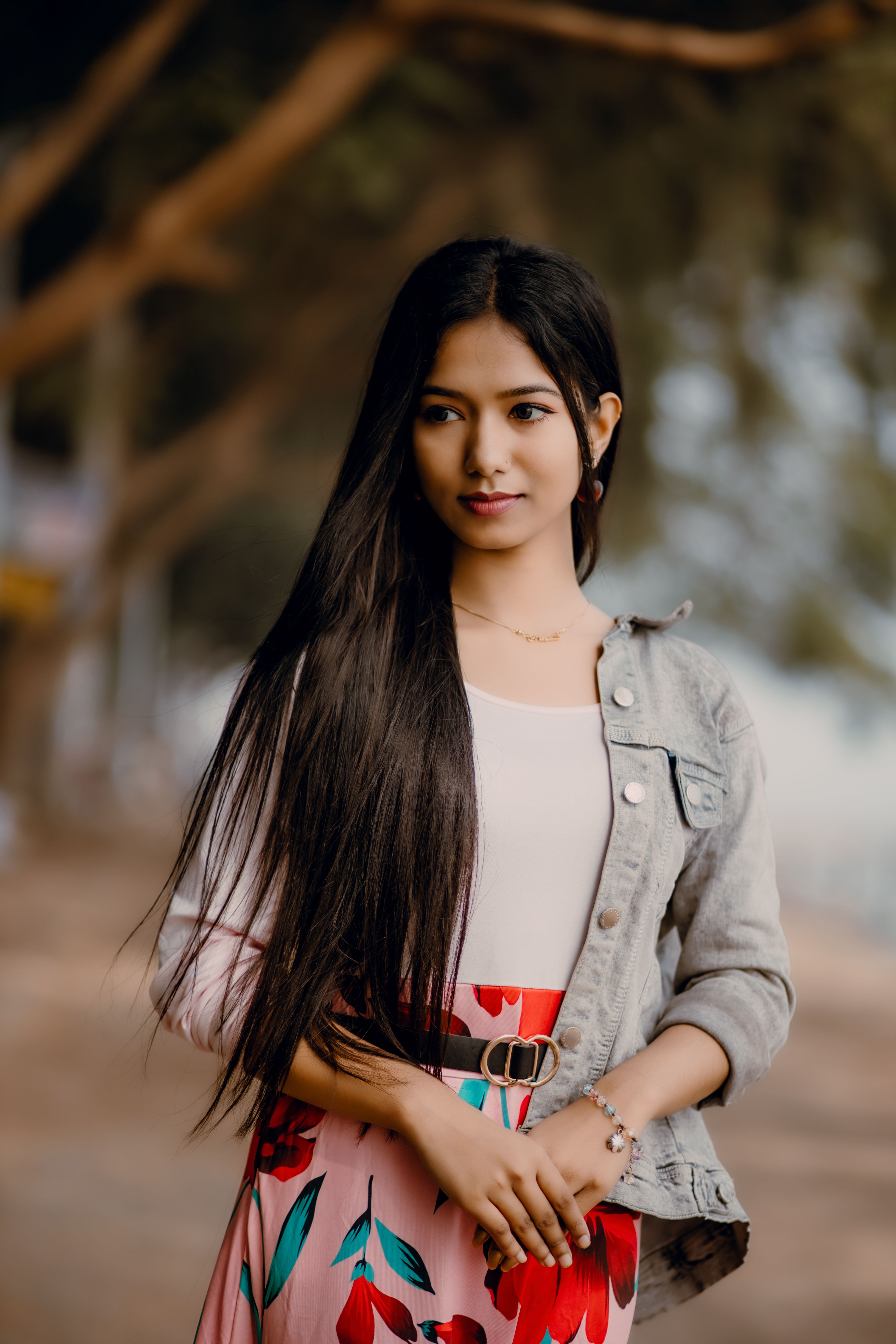 Portrait of a young woman with long hair, in a stylish outfit, standing outdoors.